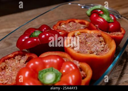 Gefüllte Paprika mit Hackfleischmischung in einer Auflaufform 28.01.25, Selters: Symbolfoto, Illustrationsbild, Symbolbild, Illustrationsfoto, Alltagsszene Gefüllte Paprika mit Hackfleischmischung in einer Auflaufform Frische, rote Paprikaschoten, gefüllt mit einer würzigen Hackfleischmischung, stehen in einer Glasauflaufform auf einem rustikalen Holztisch. Die Zubereitung ist noch nicht abgeschlossen, da die Paprika roh und ungebacken sind. Dieses klassische Gericht ist ein beliebtes Rezept in vielen Küchen weltweit. . Selters Hessen Germania *** peperoni ripieni con impasto di carne macinata in una c Foto Stock
