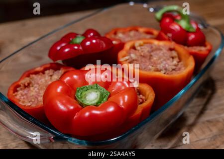 Gefüllte Paprika mit Hackfleischmischung in einer Auflaufform 28.01.25, Selters: Symbolfoto, Illustrationsbild, Symbolbild, Illustrationsfoto, Alltagsszene Gefüllte Paprika mit Hackfleischmischung in einer Auflaufform Frische, rote Paprikaschoten, gefüllt mit einer würzigen Hackfleischmischung, stehen in einer Glasauflaufform auf einem rustikalen Holztisch. Die Zubereitung ist noch nicht abgeschlossen, da die Paprika roh und ungebacken sind. Dieses klassische Gericht ist ein beliebtes Rezept in vielen Küchen weltweit. . Selters Hessen Germania *** peperoni ripieni con impasto di carne macinata in una c Foto Stock