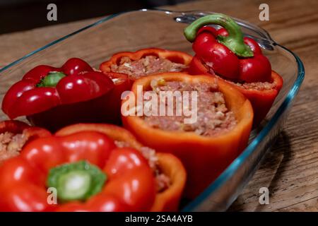 Gefüllte Paprika mit Hackfleischmischung in einer Auflaufform 28.01.25, Selters: Symbolfoto, Illustrationsbild, Symbolbild, Illustrationsfoto, Alltagsszene Gefüllte Paprika mit Hackfleischmischung in einer Auflaufform Frische, rote Paprikaschoten, gefüllt mit einer würzigen Hackfleischmischung, stehen in einer Glasauflaufform auf einem rustikalen Holztisch. Die Zubereitung ist noch nicht abgeschlossen, da die Paprika roh und ungebacken sind. Dieses klassische Gericht ist ein beliebtes Rezept in vielen Küchen weltweit. . Selters Hessen Germania *** peperoni ripieni con impasto di carne macinata in una c Foto Stock
