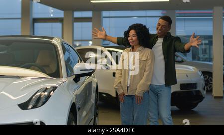 Afroamericano famiglia felice affettuosa coppia proprietari donna uomo comprare auto in concessionaria negozio nuovo auto sorpresa regalo noleggio auto eccitato Foto Stock