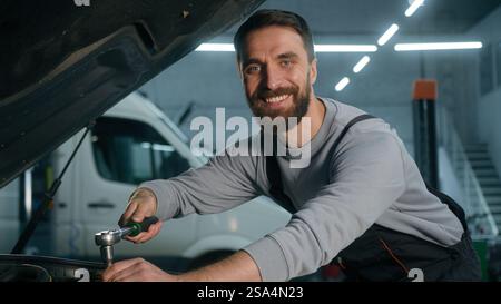 Meccanico di auto addetto alla manutenzione dei veicoli che lavora in officina utilizzando una chiave per riparare il motore aperto cofano auto adulto Caucasico MAN auto Foto Stock