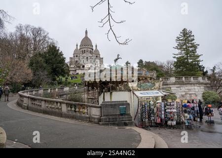 Incantevole giostra vicino all'iconica basilica di Montmartre in una giornata nuvolosa Foto Stock