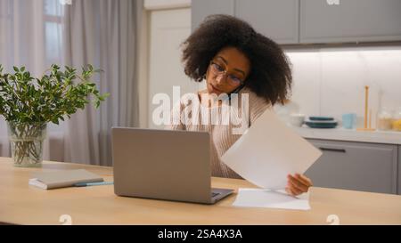 Donna afroamericana donna d'affari multitasking freelancer imprenditore d'affari che lavora laptop lontano da casa cucina ragazza etnica che parla Foto Stock