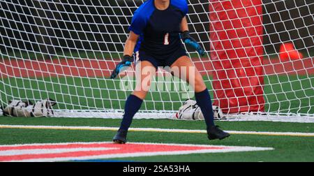 Un portiere mirato si posiziona davanti alla rete, pronto all'azione in una partita di calcio competitiva. Foto Stock