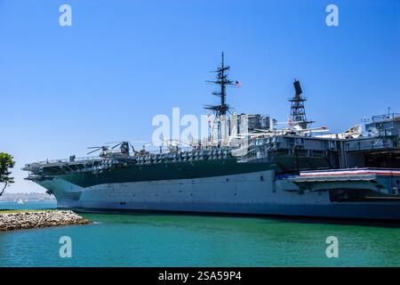 Una grande nave della marina è ancorata in un corpo d'acqua. La nave è circondata da un cielo blu e l'acqua è calma Foto Stock