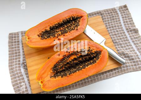Due metà di una papaya che mostra l'interno dopo essere stata tagliata su un asse di legno. Foto Stock