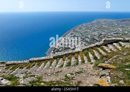 Vista dall'antica Thira che si affaccia su Perissa e sul Mar Egeo a Santorini, Grecia. Un sito storico con splendidi paesaggi costieri e vulcanici. Foto Stock