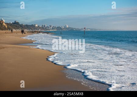 Le persone passeggiano lungo le coste sabbiose della spiaggia di Branksome a Bournemouth, godendosi il sole invernale e le splendide vedute costiere del Dorset, Inghilterra, Regno Unito Foto Stock