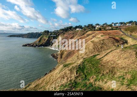 Il sole invernale illumina le splendide scogliere di Lions Head vicino al faro di Baily nella Doldrum Bay, Howth, Irlanda Foto Stock
