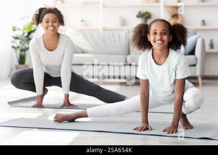 Gioiosa madre e figlia afroamericana che si estende a casa Foto Stock