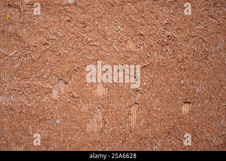 Un muro marrone con molti trucioli di legno. Il muro è ruvido e irregolare. I trucioli di legno sono sparsi su tutta la parete, creando un disordine e disordine Foto Stock