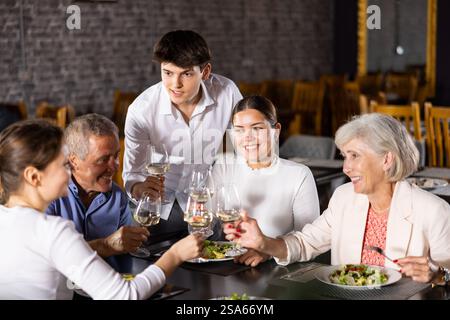 Coppia anziana che trascorre il tempo con i giovani amici al ristorante Foto Stock
