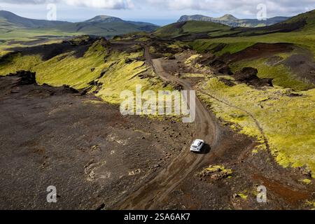 Vista aerea con droni esplorando il paesaggio della valle con un'auto bianca solitaria 4x4 su una strada sterrata per il campeggio Thakgil (Pakgil) vicino a Vik in Islanda Foto Stock