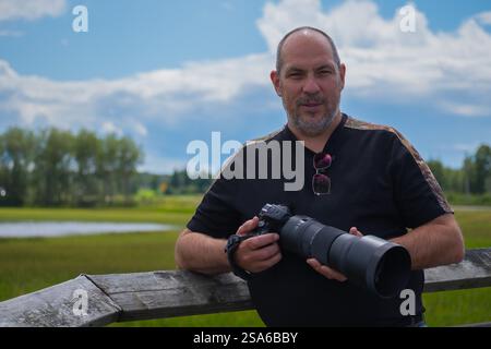 Ritratto di un uomo maturo con una macchina fotografica sullo sfondo della natura Foto Stock