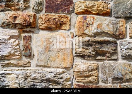 Vista ravvicinata dettagliata di un muro di pietra rustica con texture colorate e motivi unici Foto Stock