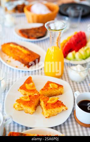 Deliziosa torta d'arancia servita a colazione con succo di frutta fresco e tazza di caffè caldo Foto Stock