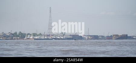 Il fiume Barito funge da rotta di trasporto vitale per le comunità locali, mostrando chiatte di carbone ancorate lungo le sue rive in una città in Indonesia. Foto Stock