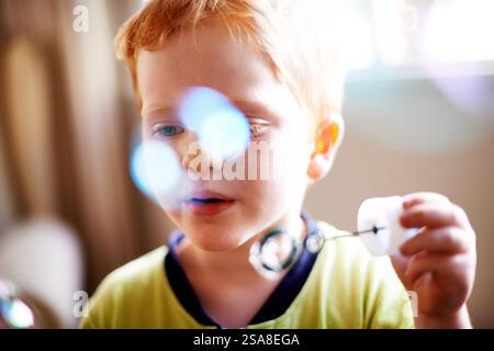 Ragazzi, bambini e bolle soffianti giocando per stimolare i sensi, sviluppare i bambini e svolgere attività creative. Bokeh, persona e bacchetta con sapone liquido Foto Stock