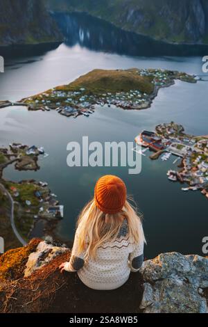 Donna che viaggia nelle isole Lofoten ragazza seduta sul monte Reinebringen in Norvegia vacanze attive viaggiatore da solo che indossa un maglione scandinavo all'aperto Foto Stock