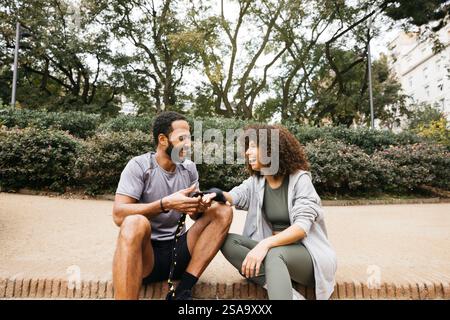 Un allenatore di pugilato assiste una giovane donna avvolgendosi il polso in un nastro durante l'allenamento in un parco all'aperto. Foto Stock