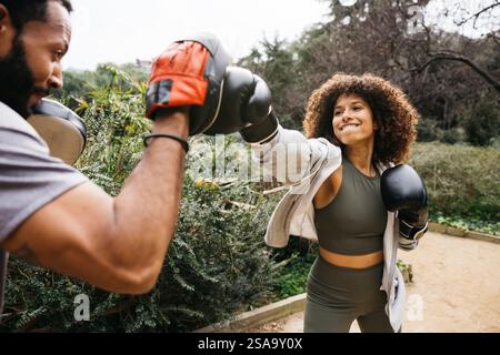 Una giovane pugilata con il suo allenatore in un parco urbano, mostrando determinazione e perseveranza nell'esercizio fisico. Foto Stock