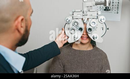 Optometrista che esegue l'esame oculare con il paziente utilizzando il Phoropter Foto Stock