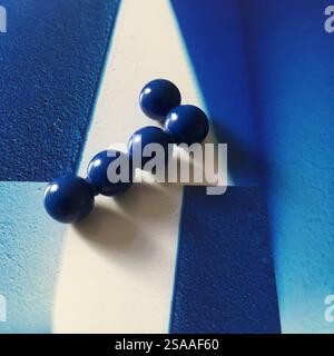 Composizione minimalista con una serie di sfere blu disposte su un vibrante sfondo astratto in tonalità sfumate. Foto Stock