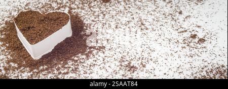 Caffè appena macinato in un cuore bianco su un tavolo bianco. Caffè nel mio cuore. L'amore per il caffè fresco. Profondità di campo ridotta. Foto Stock