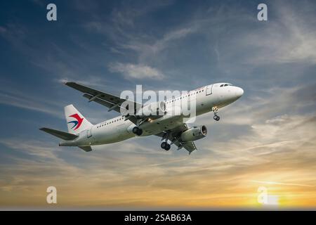 China Eastern Airline A319 aereo passeggeri in volo nel cielo. L'aereo contro il cielo del tramonto in preparazione per l'atterraggio all'aeroporto. foto di viaggio, Foto Stock