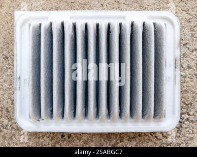 Primo piano di un filtro dell'aria usato coperto di polvere e sporcizia dopo un uso prolungato in condizioni di guida urbane, vista frontale con la copia sp Foto Stock