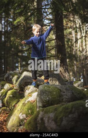 un bambino di 7 anni cammina sulle rocce nella foresta di montagna Foto Stock