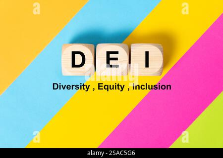 Parole DEI su cubi di legno su sfondo colorato, che significa diversità, equità e inclusione. Foto Stock