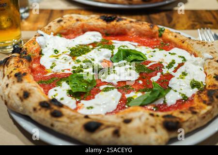 Deliziosa pizza italiana con burrata, basilico fresco e salsa al pesto Foto Stock