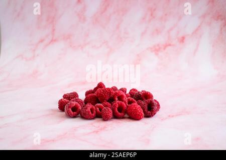 Molti lamponi maturi freschi su sfondo rosa. Foto Stock