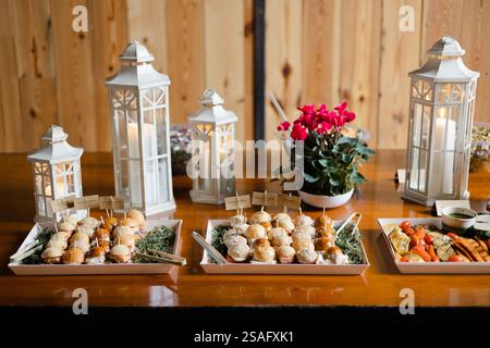 Un invitante assortimento di antipasti e verdure fresche è esposto sui vassoi. Le eleganti lanterne e i fiori in vaso esaltano la calda atmosfera di questo hotel Foto Stock