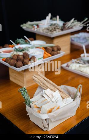Vari tipi di antipasti sono disposti artisticamente su tavoli di legno, con una selezione di salse, verdure e spuntini saporiti, invitante gue Foto Stock