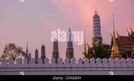 Le guglie del tempio si innalzano su uno splendido cielo pastello durante il tramonto a Bangkok, Thailandia. Questo momento tranquillo cattura la bellezza dell'architettura sacra del tempio Wat Phra Kaew, il Grand Royal Palace Foto Stock