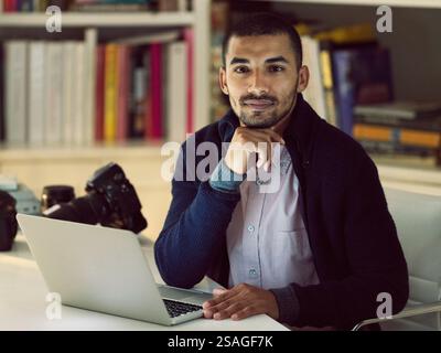 Casa, uomo d'affari e fotografo con laptop per ritratti, editing o ritocco di foto con freelance. Lavoro notturno, lavoro in remoto o creazione di contenuti con Foto Stock