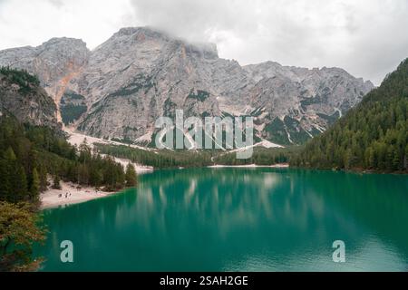 Uno splendido lago alpino incastonato nel cuore delle Dolomiti, Italia. Le acque cristalline e turchesi del Lago di Braies riflettono perfettamente l'aspro paesaggio Foto Stock