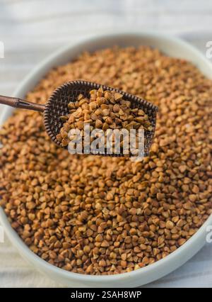 Ciotola di grano saraceno arrosto con una paletta vintage, tavolo rustico in legno, primo piano. Foto di alta qualità Foto Stock