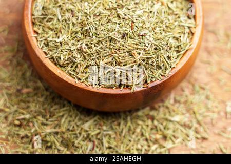 Ciotola di legno riempita con parti medicinali essiccate di piante di ipposeto. Foglie di erbe e steli. Concetto di erbe curative. Macro Foto Stock
