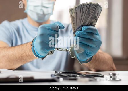 Un medico con banconote in dollari e manette. concetto di corruzione medica, corruzione, crimine. Foto Stock