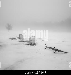 Immagine minimalista di recinzioni metalliche in un campo coperto di neve Foto Stock