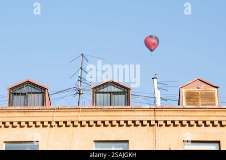 Un colorato pallone aerostatico che si innalza in un cielo azzurro e limpido durante una giornata di sole Foto Stock