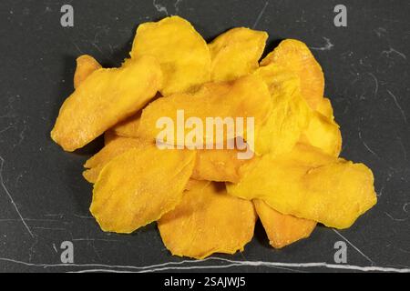 Vista dall'alto delle fette di mango essiccate pressate su sfondo scuro. Foto Stock