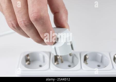 Primo piano della mano della donna che inserisce la spina elettrica nella presa. Collegamento di dispositivi elettrici. Foto Stock