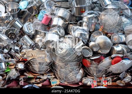 Un'enorme pila di utensili da cucina, pentole, padelle e accessori, impilati a caso uno sull'altro per consentire ai clienti di scegliere. Foto Stock