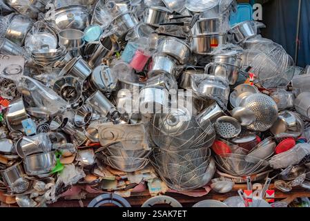 Un'enorme pila di utensili da cucina, pentole, padelle e accessori, impilati a caso uno sull'altro per consentire ai clienti di scegliere. Foto Stock
