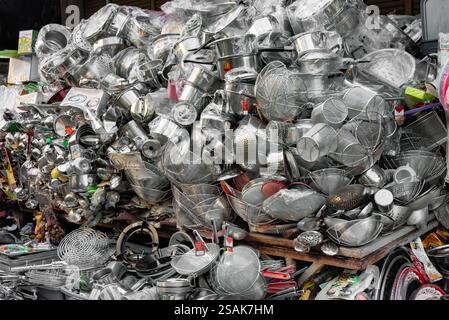 Un'enorme pila di utensili da cucina, pentole, padelle e accessori, impilati a caso uno sull'altro per consentire ai clienti di scegliere. Foto Stock