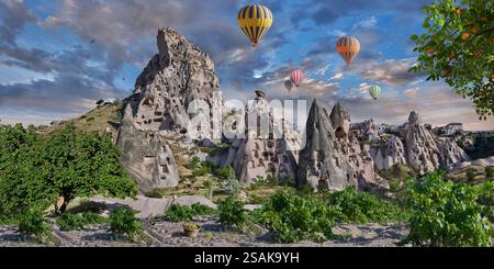 Mongolfiere che volano i turisti sopra il castello di Uchisar, le formazioni rocciose del Camino delle fate, su un volo all'alba, in Cappadocia Turchia Foto Stock